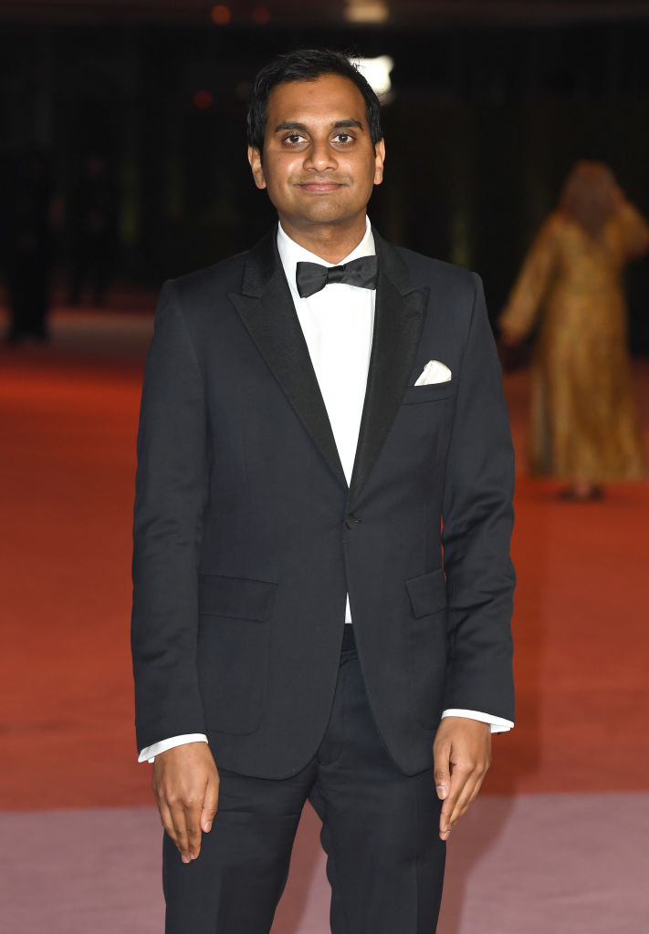 Aziz in a tuxedo with bow tie standing on a red carpet