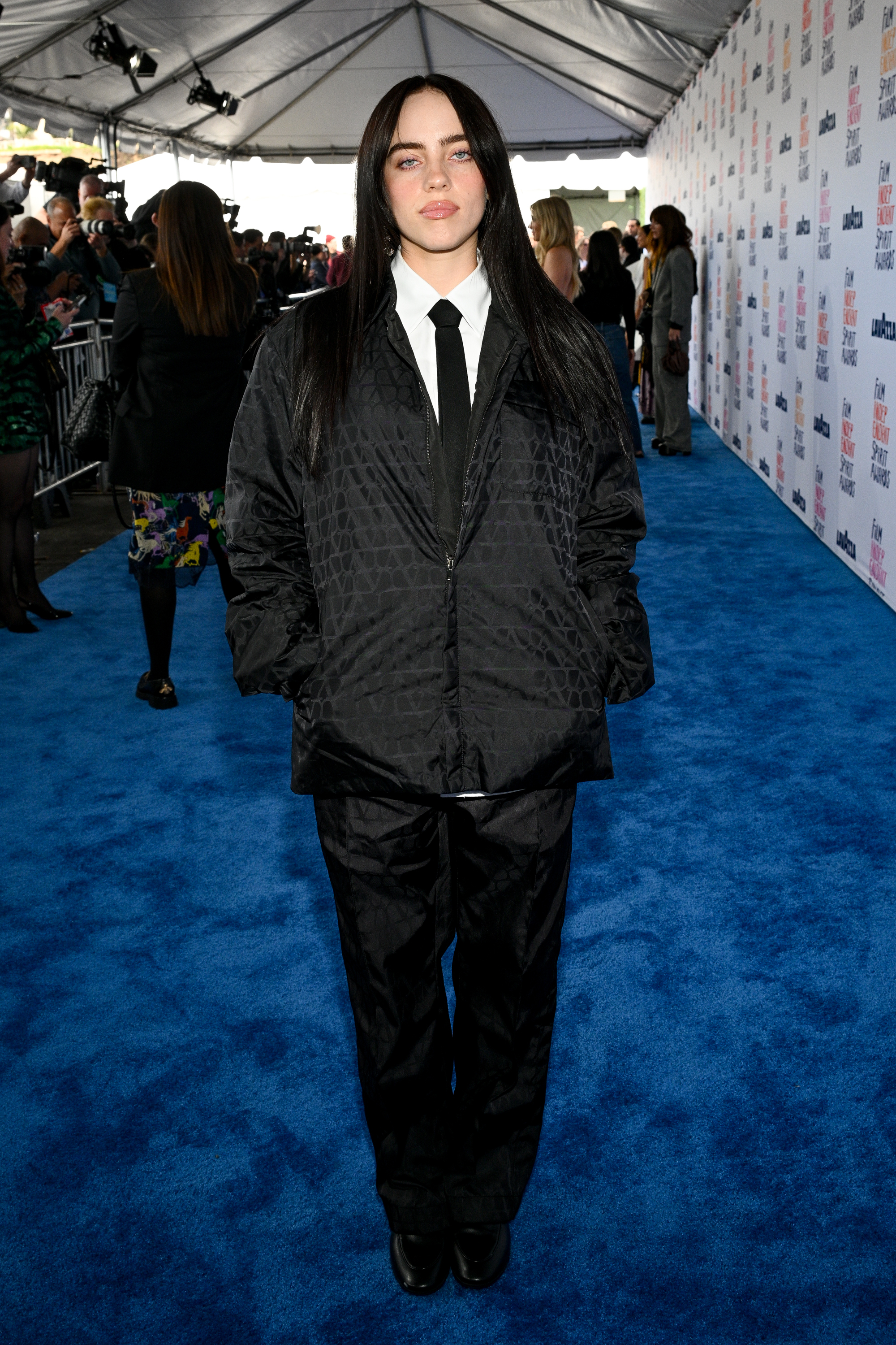 Billie Eilish in an oversized patterned suit on a blue carpet event