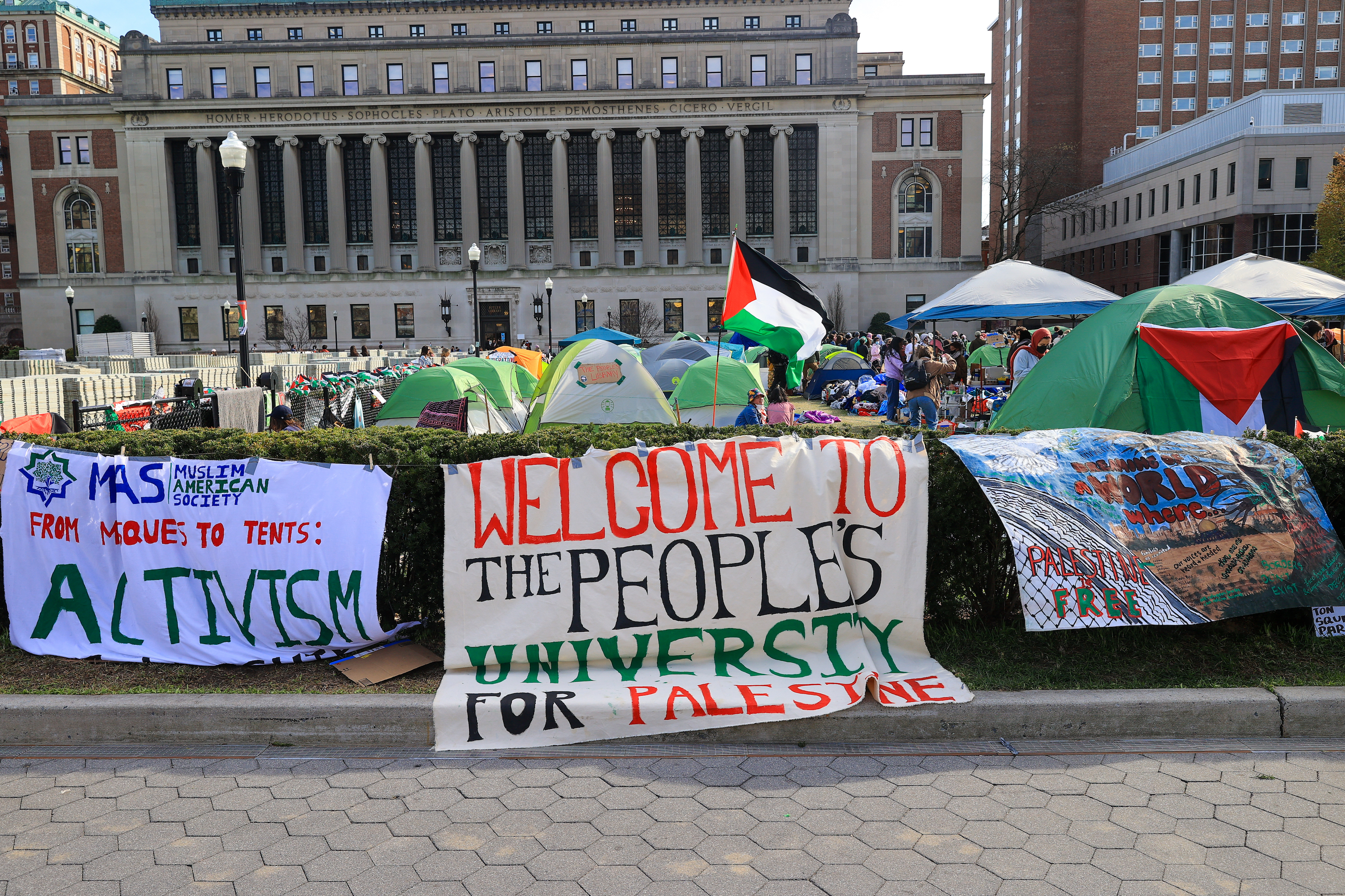 Protest camp with signs supporting Palestine in front of a building