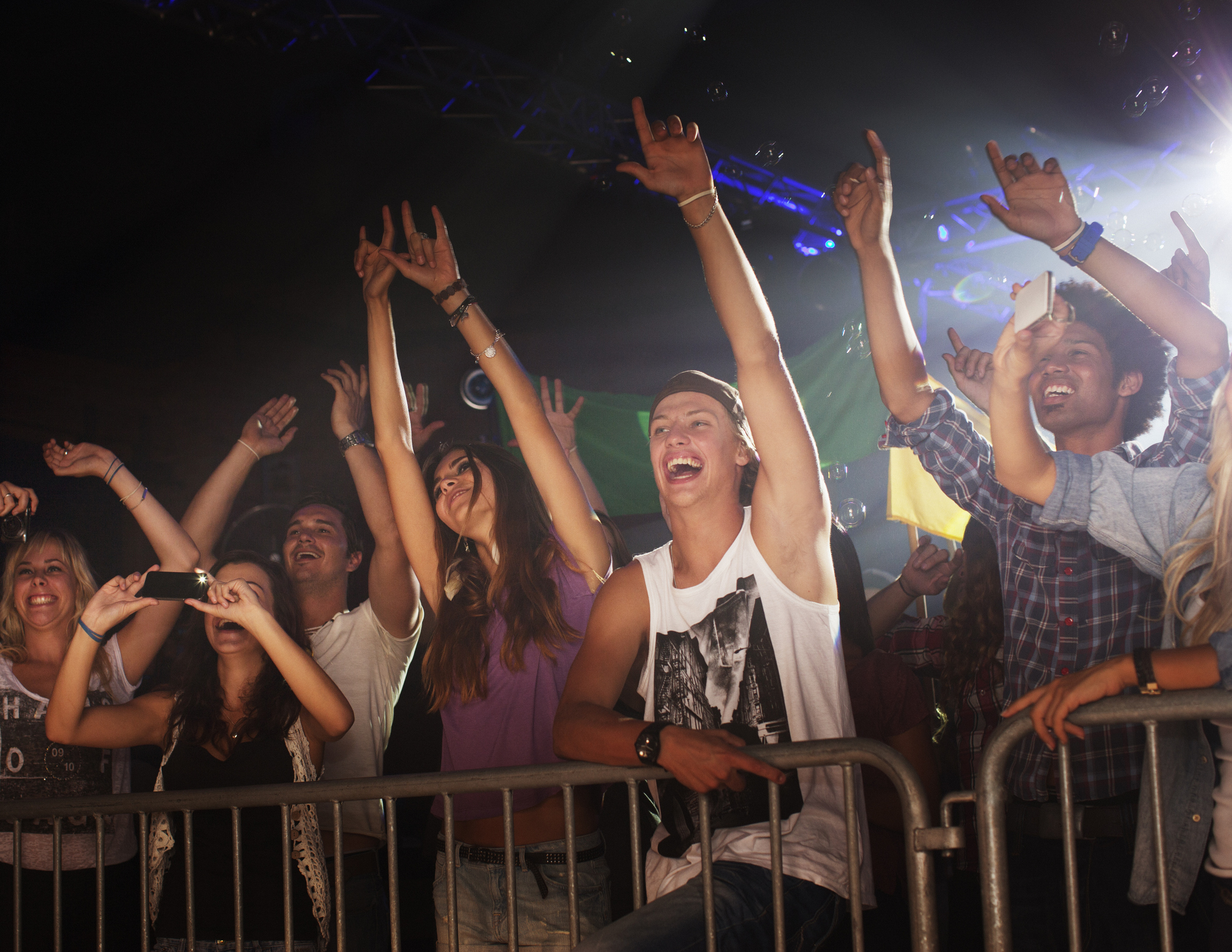 Group of people cheering at a concert, front row, with raised hands, showing excitement and enjoyment