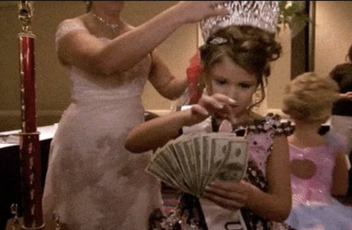 Young pageant winner holding cash with adult behind