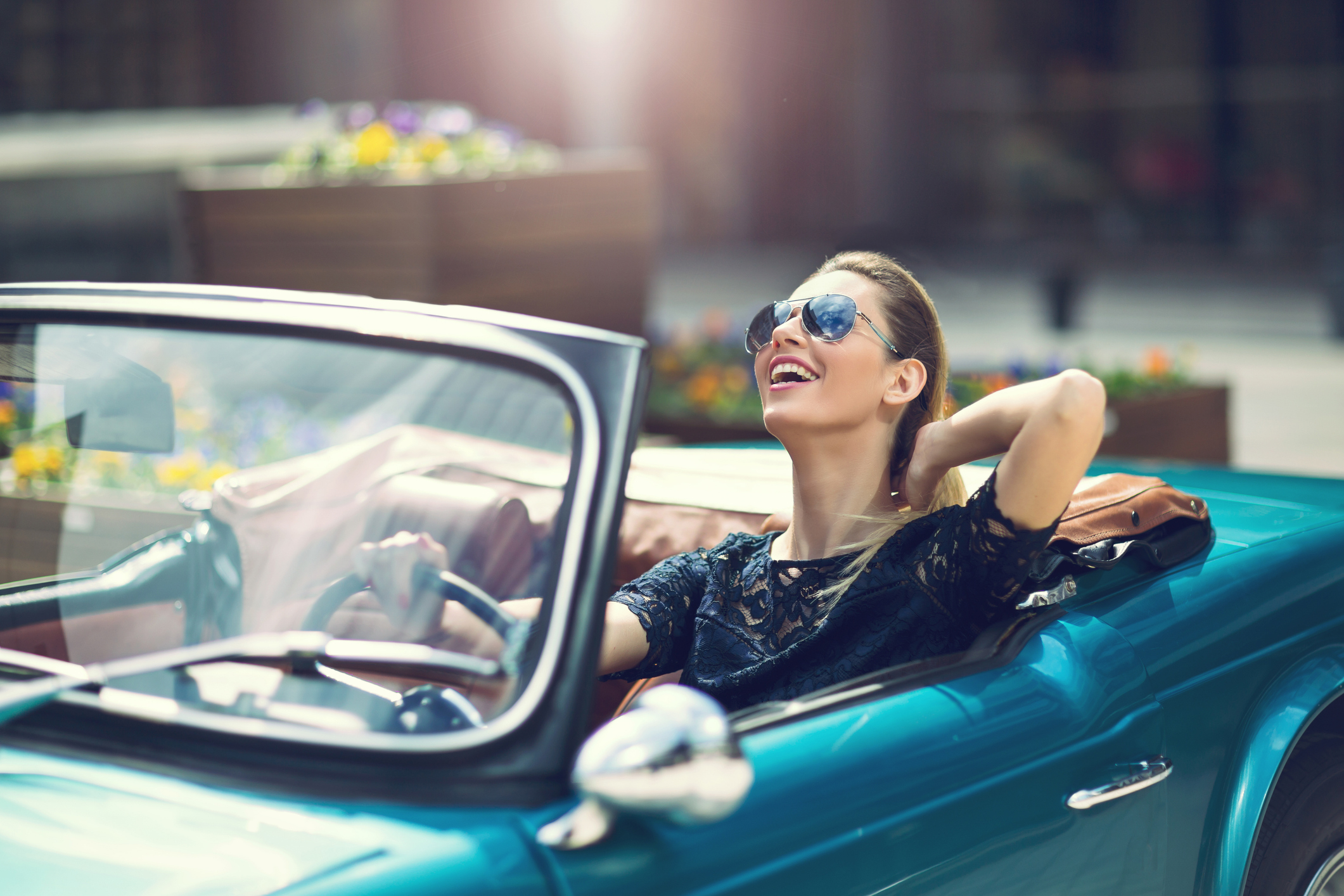Woman in sunglasses relaxing in a classic car, expressing joy or freedom