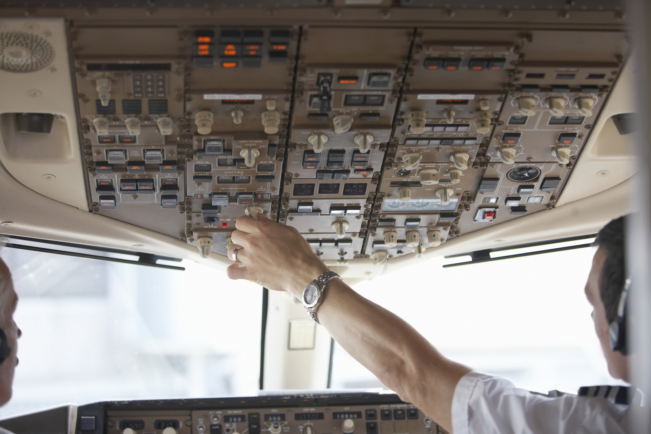 Pilot adjusting controls in cockpit overhead panel