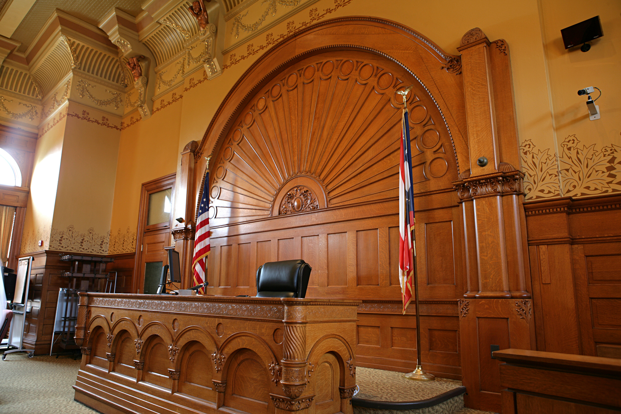 Empty judge&#x27;s bench in a traditional courtroom with ornate woodwork and the United States flag to the side