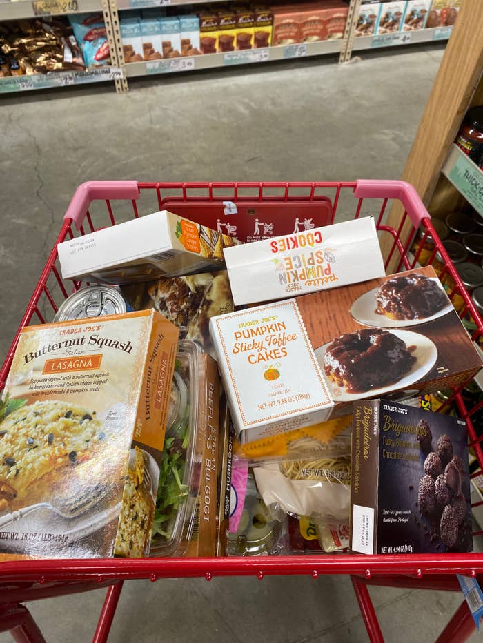 Shopping cart filled with various frozen foods including vegetarian lasagna and pumpkin sticky toffee pudding
