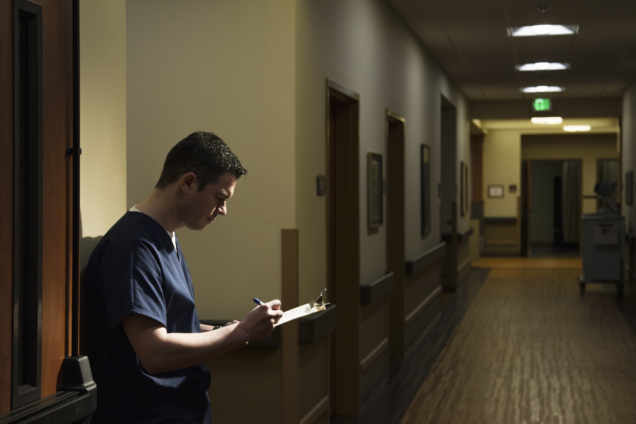 Healthcare worker in scrubs reviewing notes in a hospital corridor