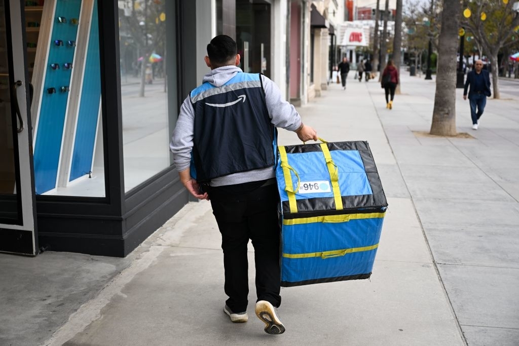 A delivery person from behind walking with an insulated food delivery bag