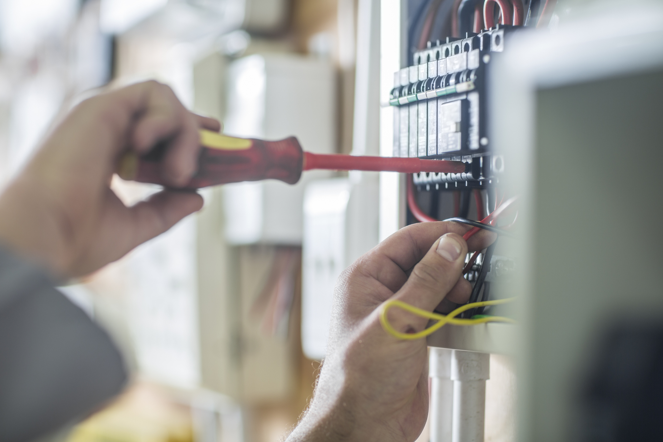 Person using a screwdriver on electrical panel wires