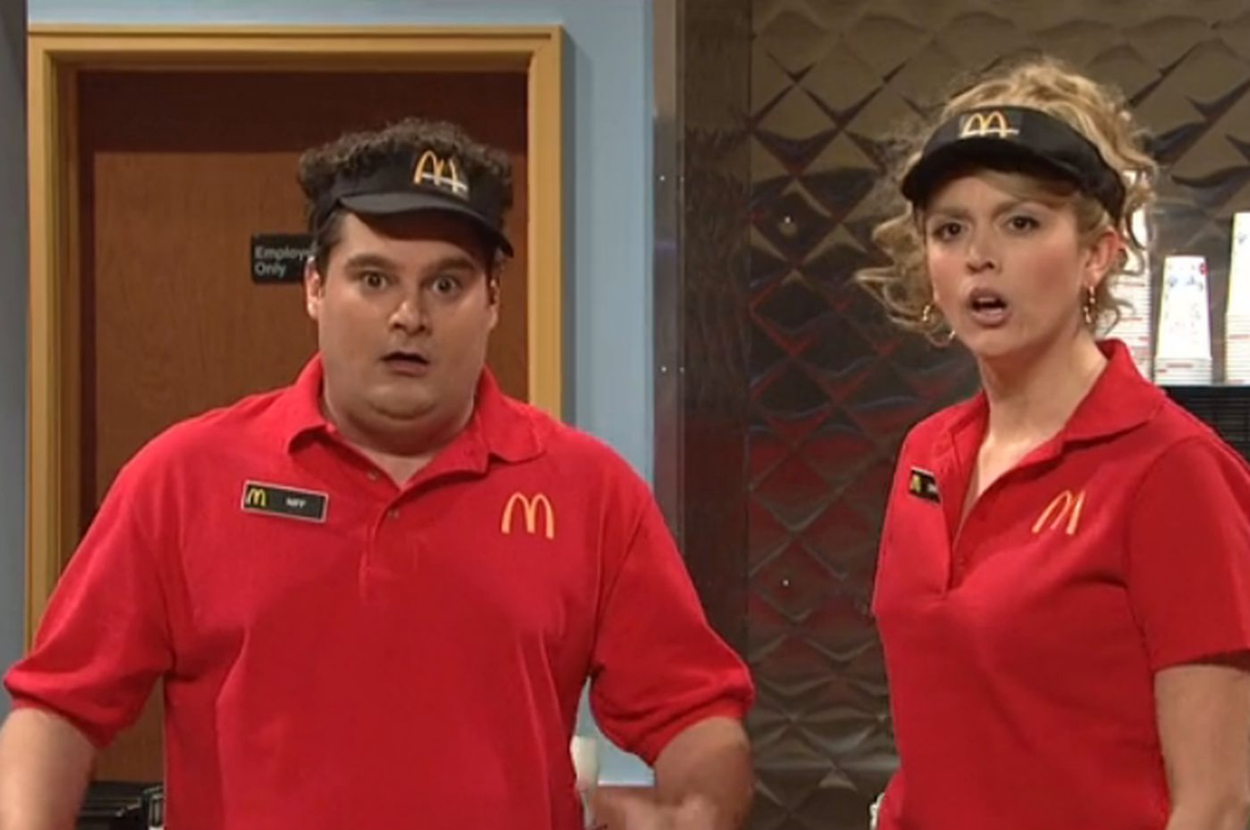 Two actors in McDonald's uniforms on a TV show set, portraying employees, with comedic expressions