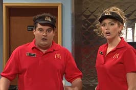 Two actors in McDonald's uniforms on a TV show set, portraying employees, with comedic expressions