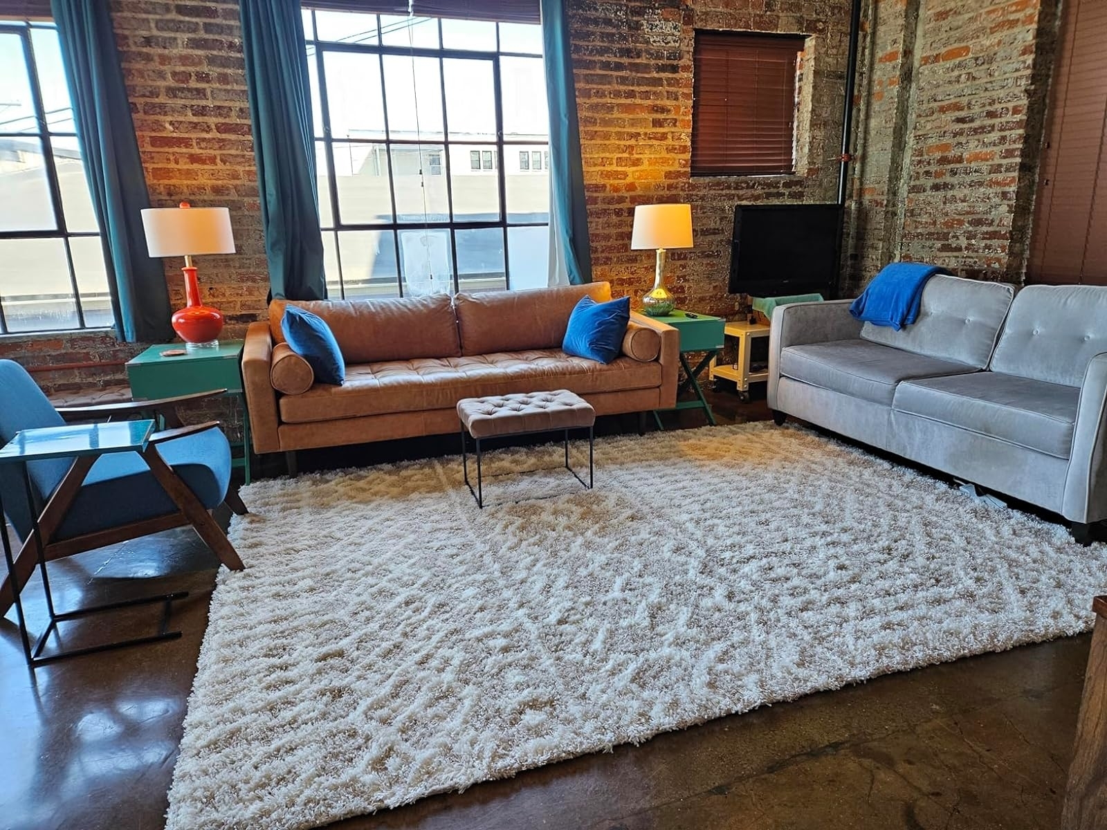 Loft living room with exposed brick walls, two sofas, a rug, and a TV
