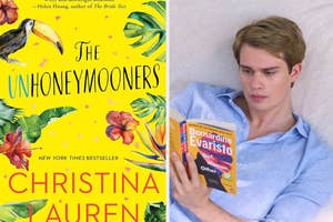 Nicholas Galitzine lying down holding a book with "The Unhoneymooners" by Christina Lauren cover visible