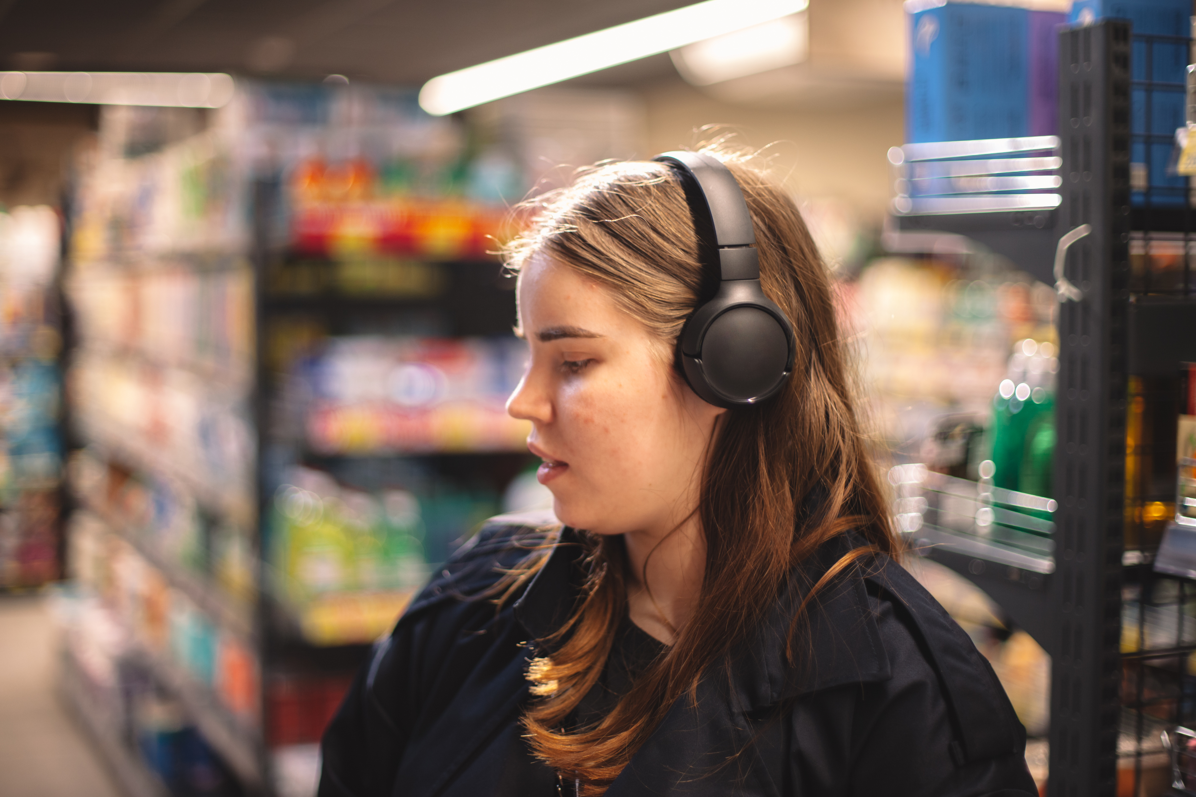 Woman with headphones shopping in a grocery store aisle