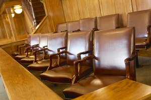 Row of empty leather chairs inside a traditional wood-paneled room, possibly a courtroom or formal setting