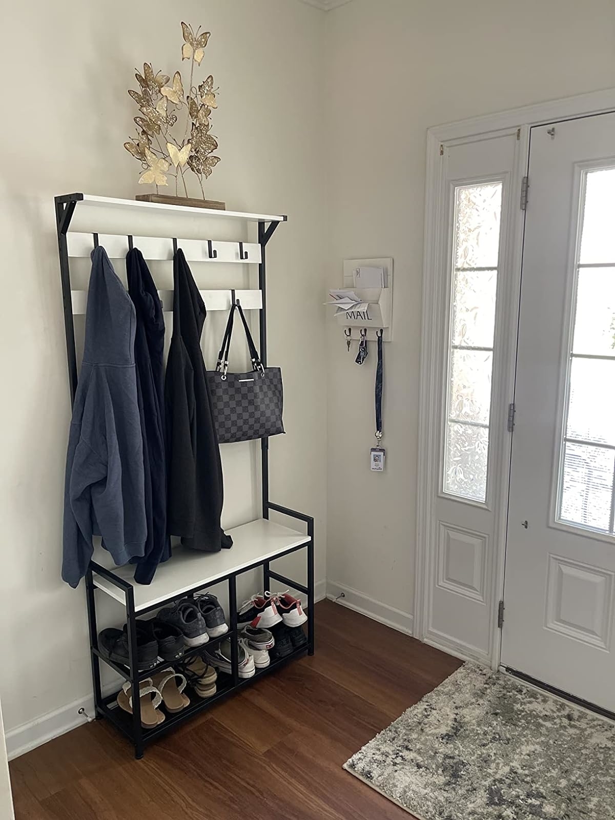 An organized entryway with a coat rack, a shelving unit with shoes, wall decor, and a door