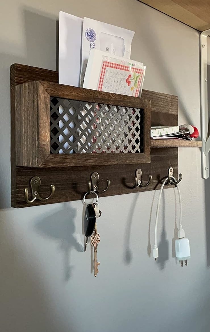 A wall-mounted organizational shelf with slots for mail and hooks for keys and cables