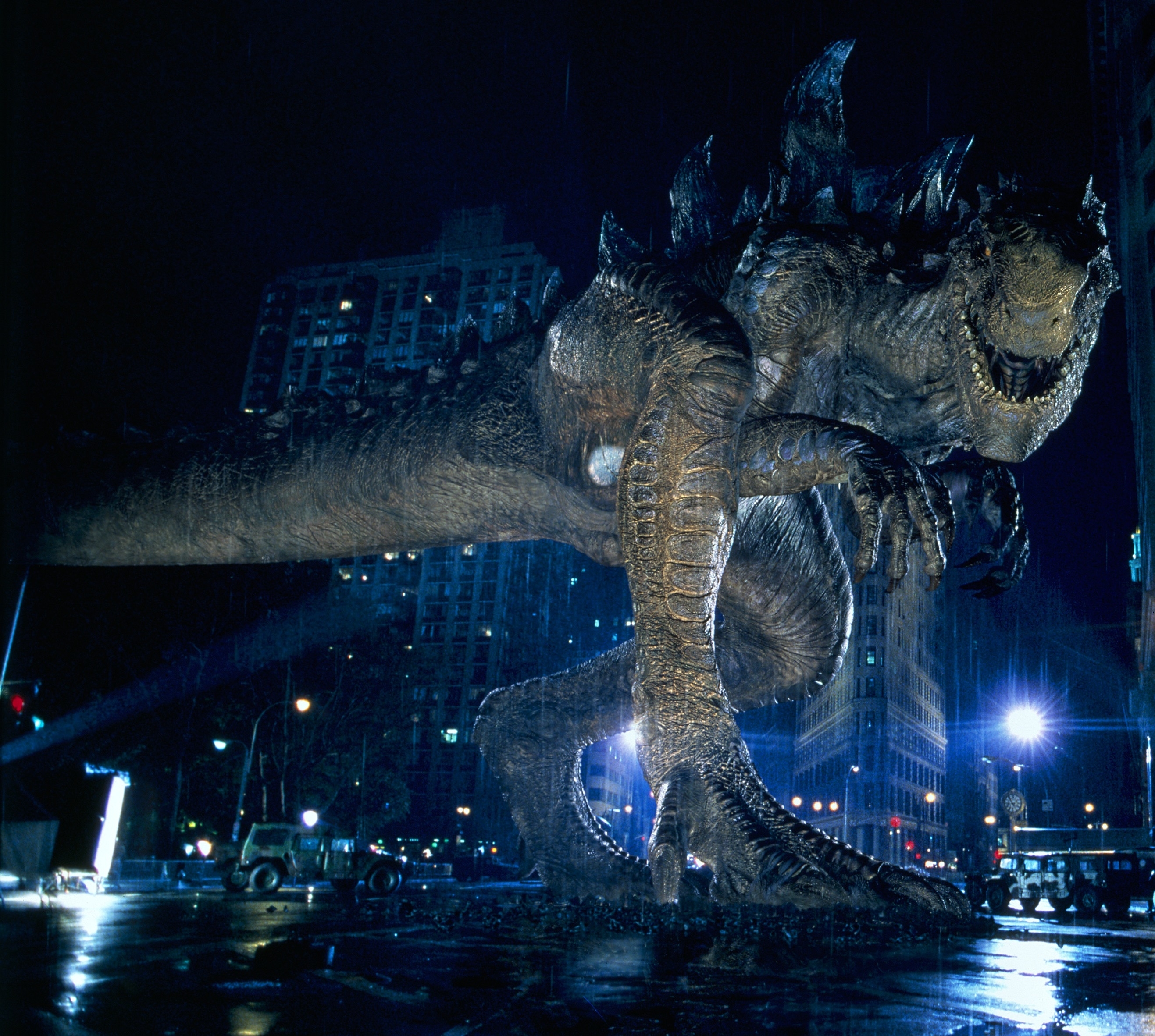 An animatronic dinosaur statue towers over an urban street at night
