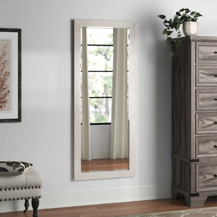 the mirror in distressed white mounted vertically on a wall
