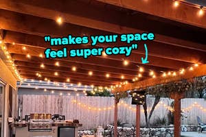 String lights hung under a patio awning with the quote "makes your space feel super cozy"