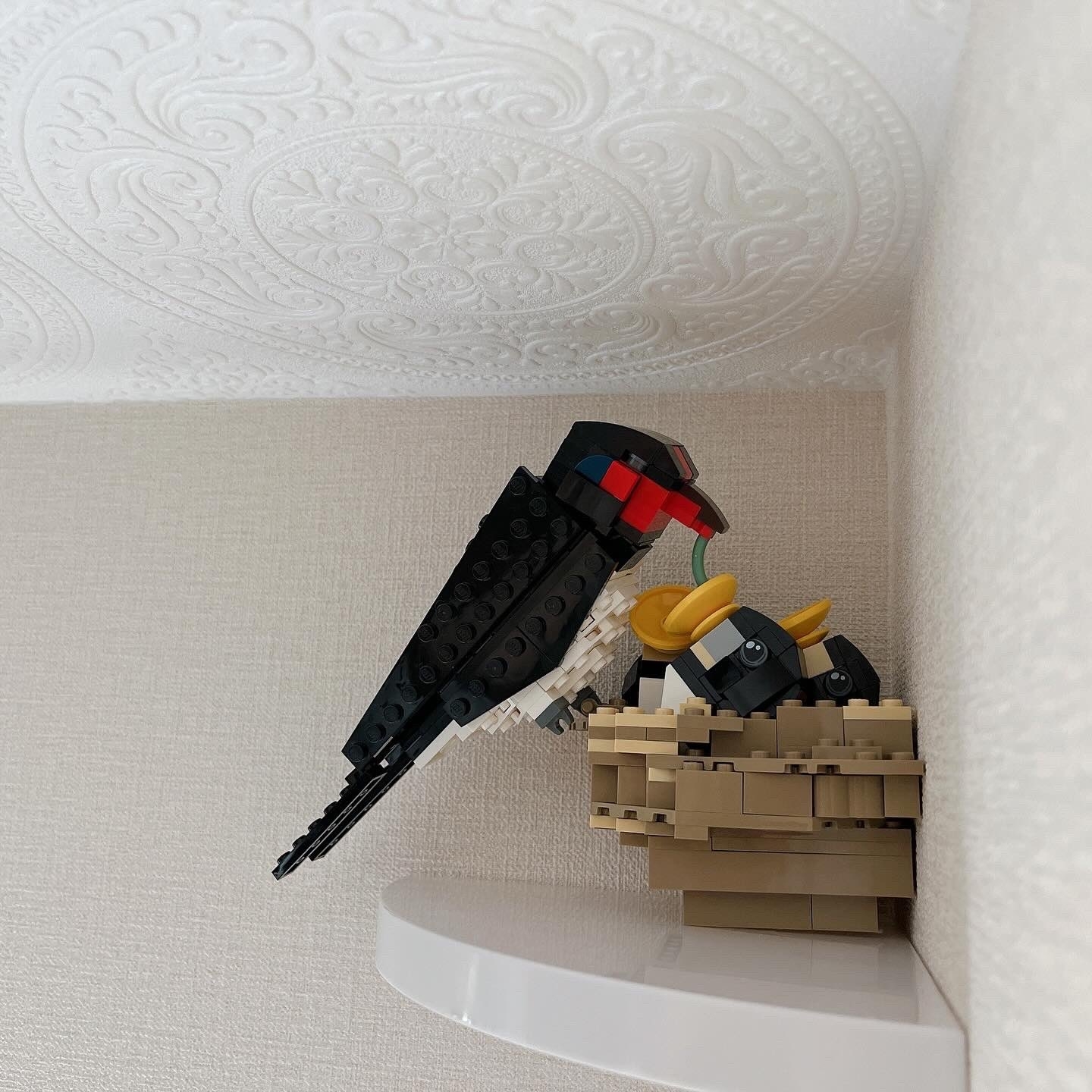 レゴで作られた鳥が壁に取り付けられている様子。