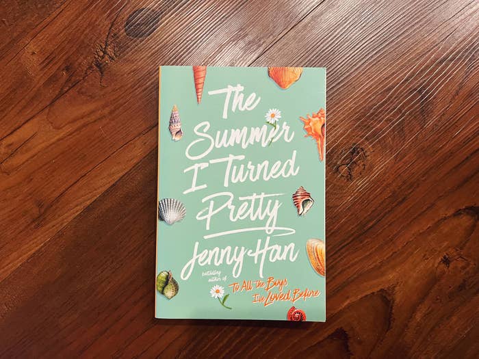 A book titled &quot;The Summer I Turned Pretty&quot; by Jenny Han, author of &quot;To All the Boys I’ve Loved Before,&quot; laying on a wooden surface