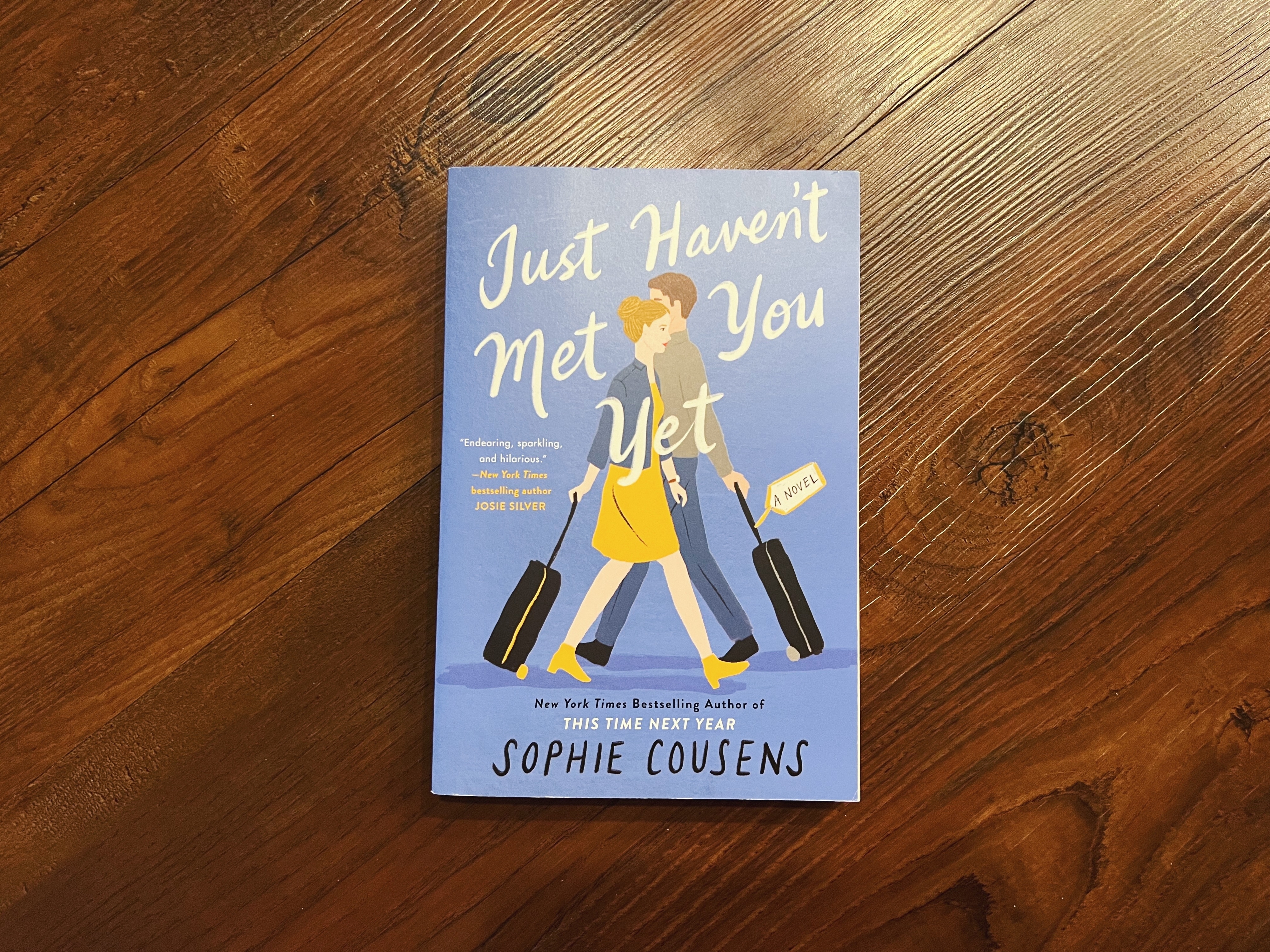 Book cover of &quot;Just Haven&#x27;t Met You Yet&quot; by Sophie Cousens, featuring illustrated woman walking with luggage