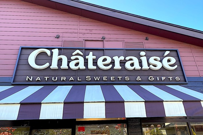 Storefront sign of ‘Châteraisé Naturals Sweets & Gifts’ above striped awning