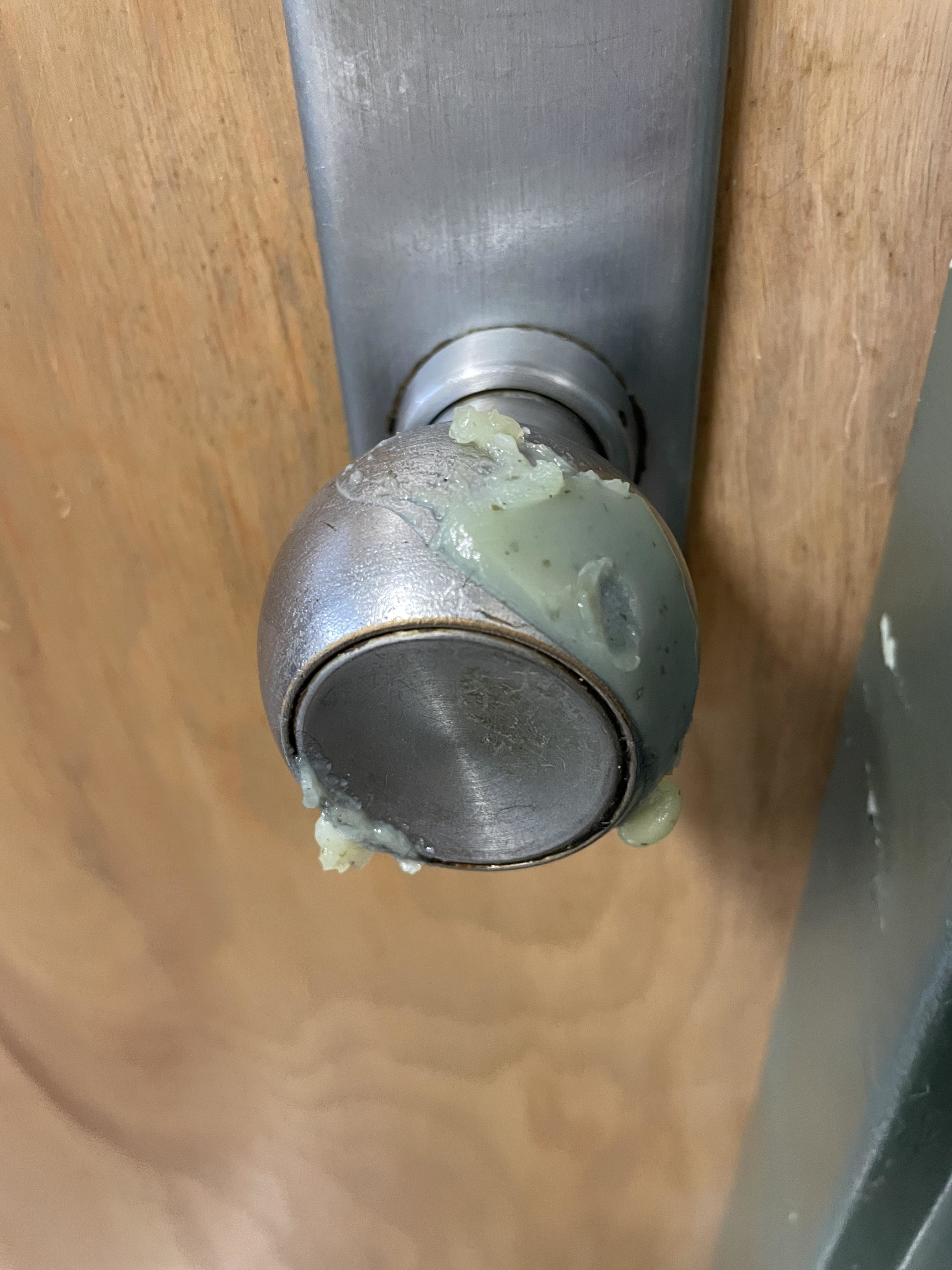 A doorknob with a sticky green substance on it