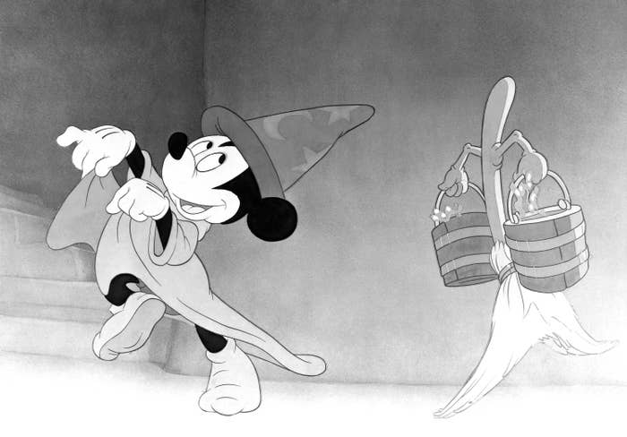 Mickey Mouse in a wizard&#x27;s hat and robe, commanding a broom that carries buckets of water