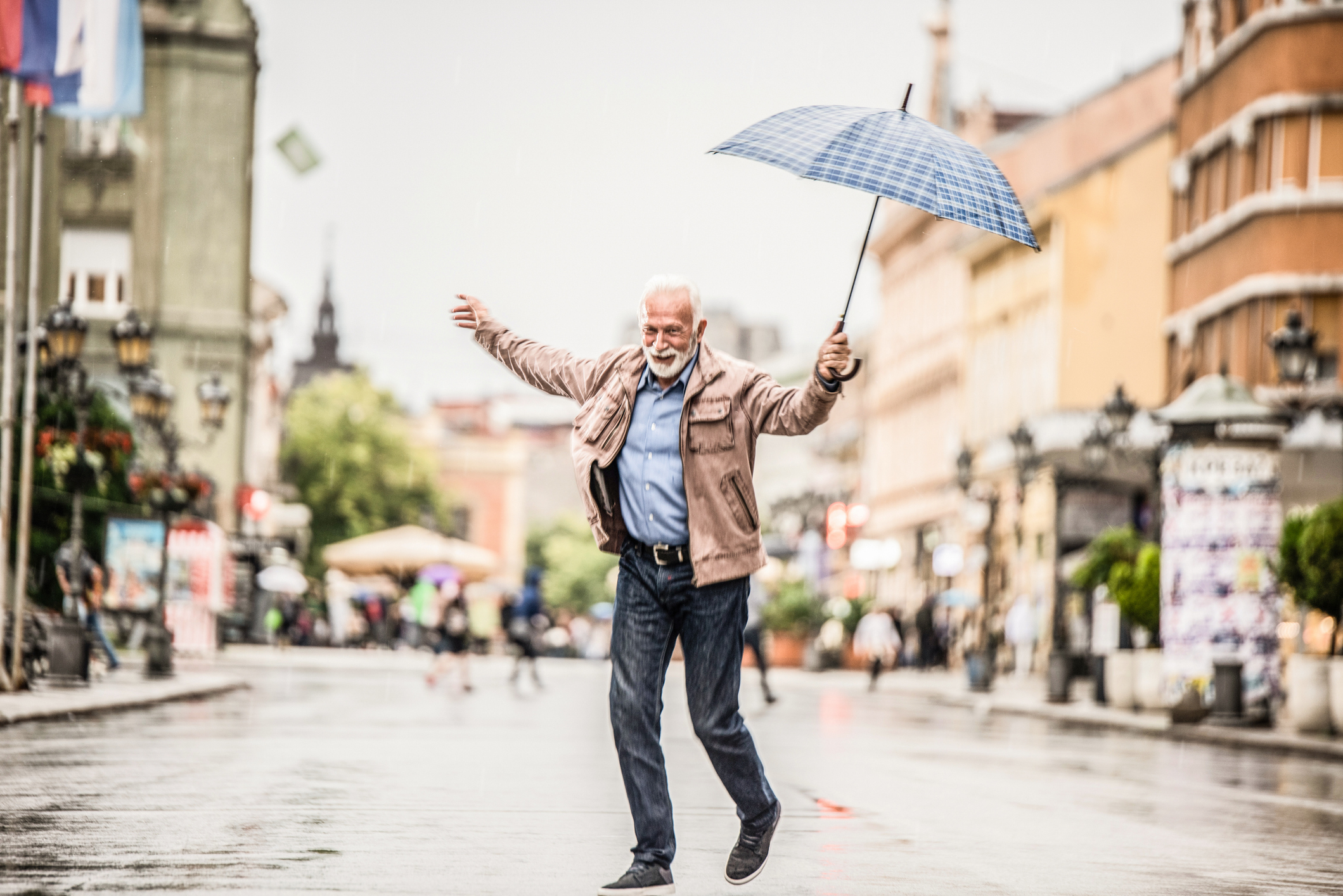 Person jubilantly holding an umbrella on a street, expressing joy
