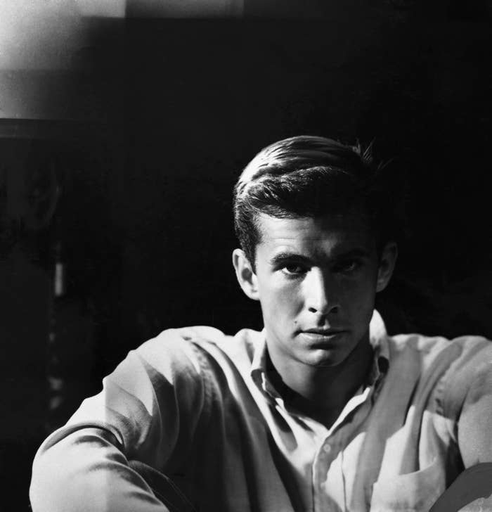 Black and white photo of a man in a buttoned shirt, looking pensively to the side