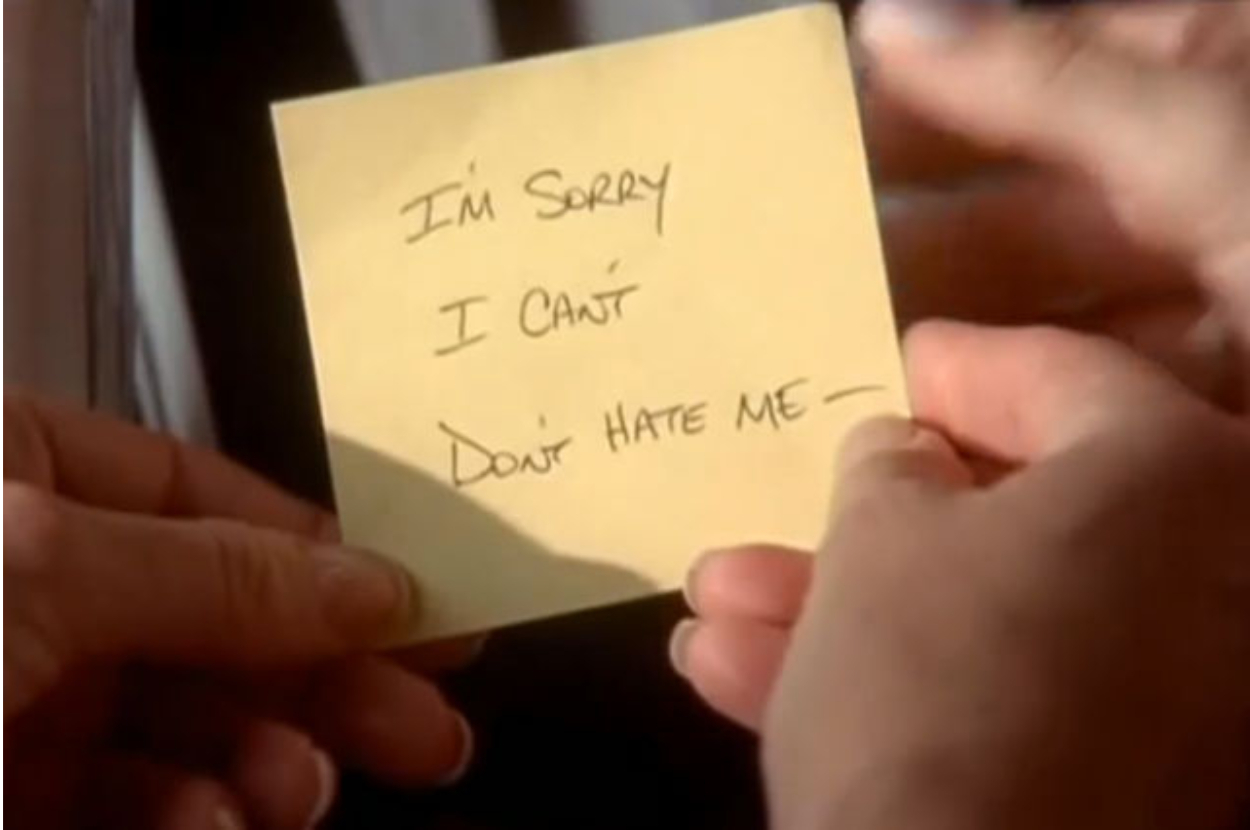 A hand holding a yellow sticky note with handwritten text: &quot;I&#x27;m sorry I can&#x27;t, Don&#x27;t hate me&quot;
