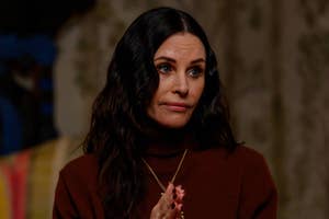 Courteney Cox wearing a turtleneck, looking concerned in a scene
