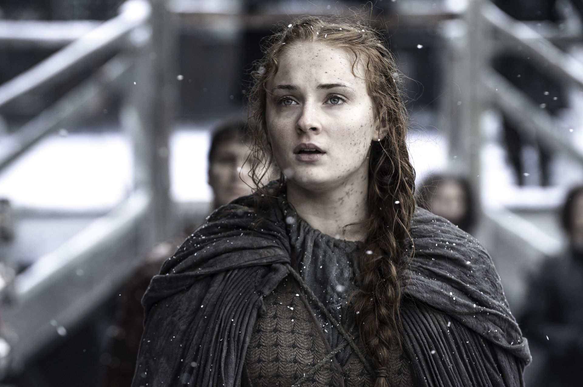 Sansa Stark from Game of Thrones, looking upwards with a worried expression, wearing a textured cape and dress