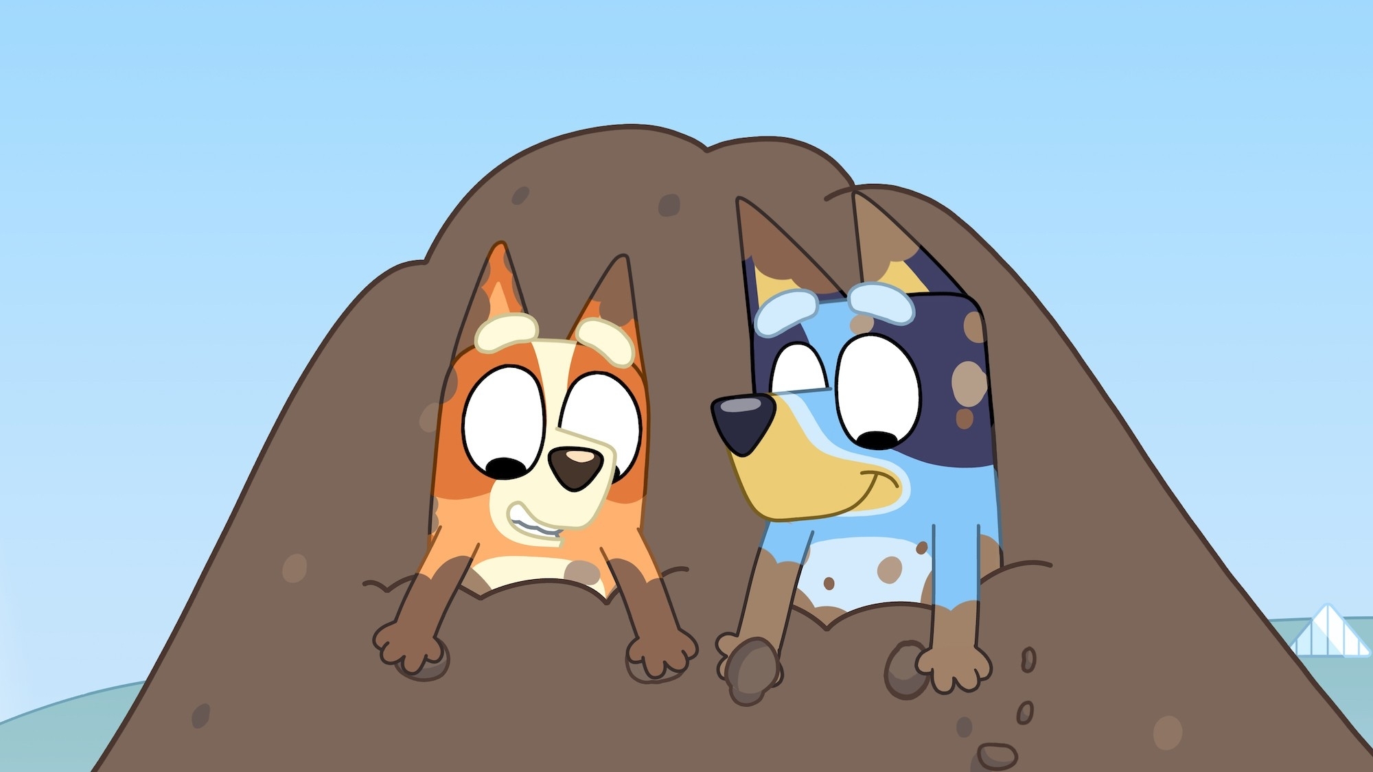 Animated characters Bluey and Bingo peek out from a dirt mound in the show &quot;Bluey.&quot;
