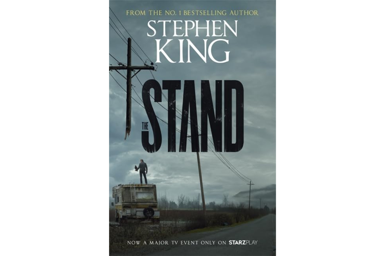Book cover of Stephen King&#x27;s &quot;The Stand&quot; with a person on a vehicle and desolate backdrop