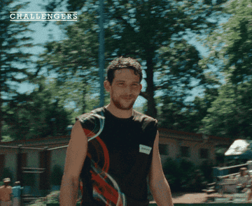 Hombre sonriendo mientras camina al aire libre, con vestimenta deportiva y gesto amigable