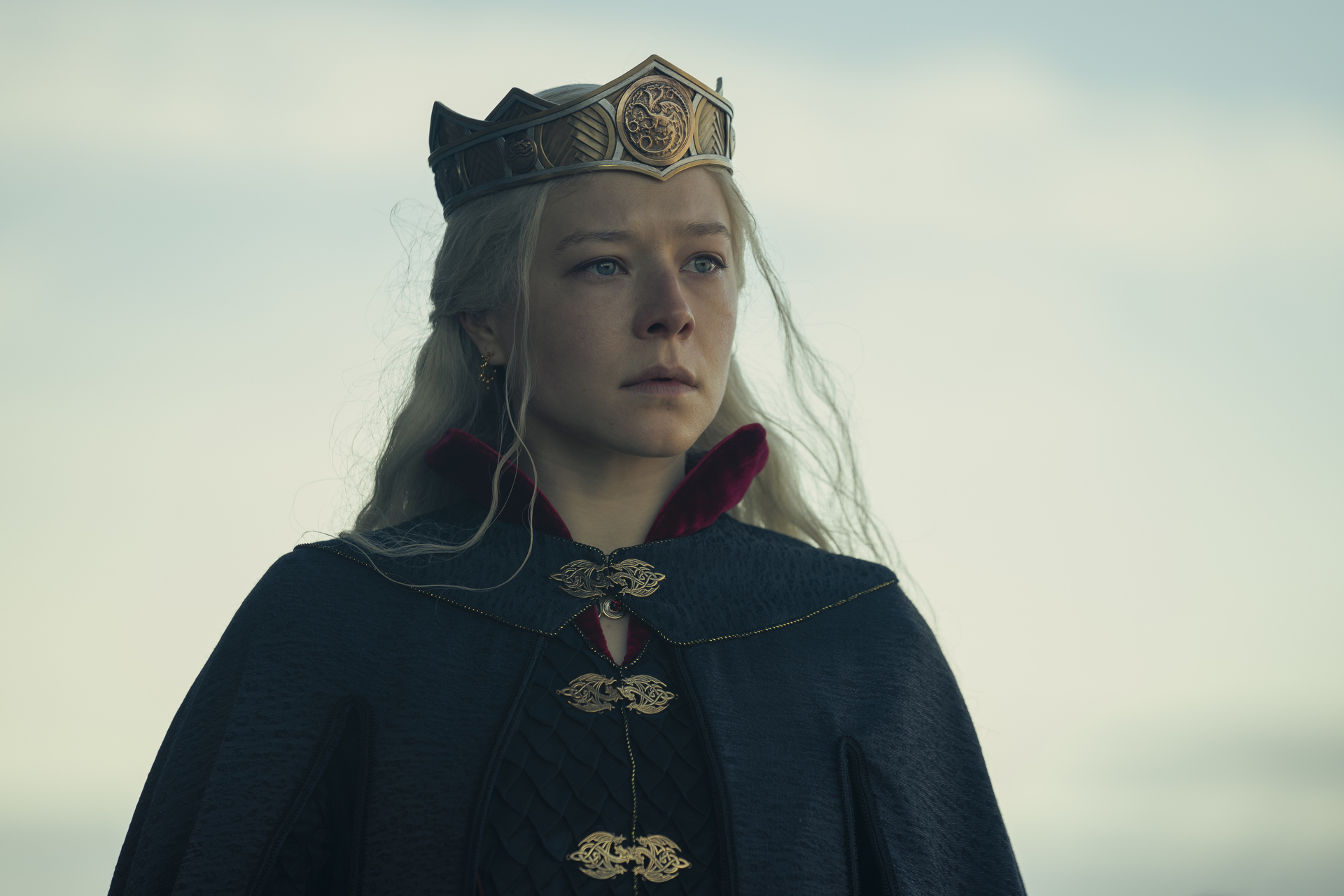 Person in royal attire with crown, gazing into distance, from TV show