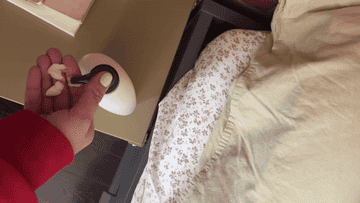 A hand placing a tracking device onto the frame of a bed for location monitoring purposes