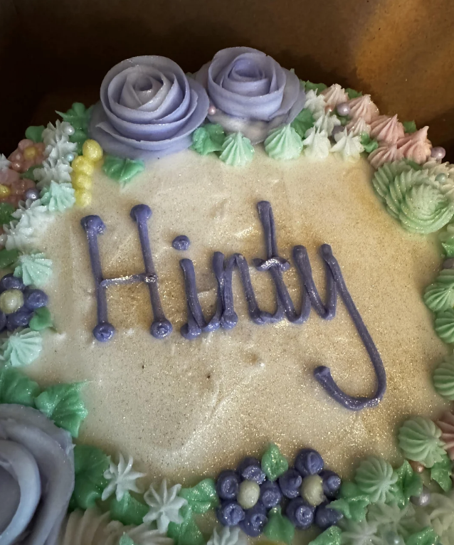 Decorated cake with &quot;Hindy&quot; written on it, surrounded by icing flowers and pearls