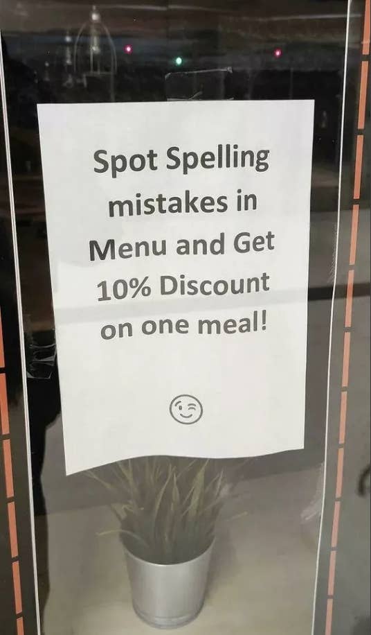 Sign on glass door offering a 10% discount for spotting spelling mistakes in the menu