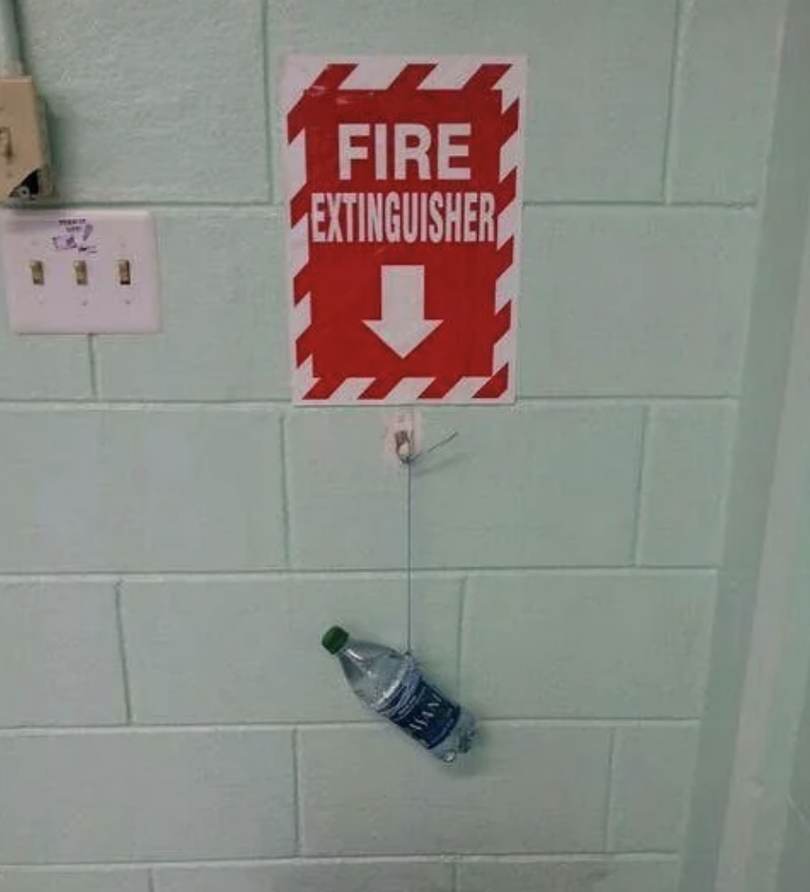 Sign reading &quot;FIRE EXTINGUISHER&quot; with an arrow pointing to a water bottle on a hook
