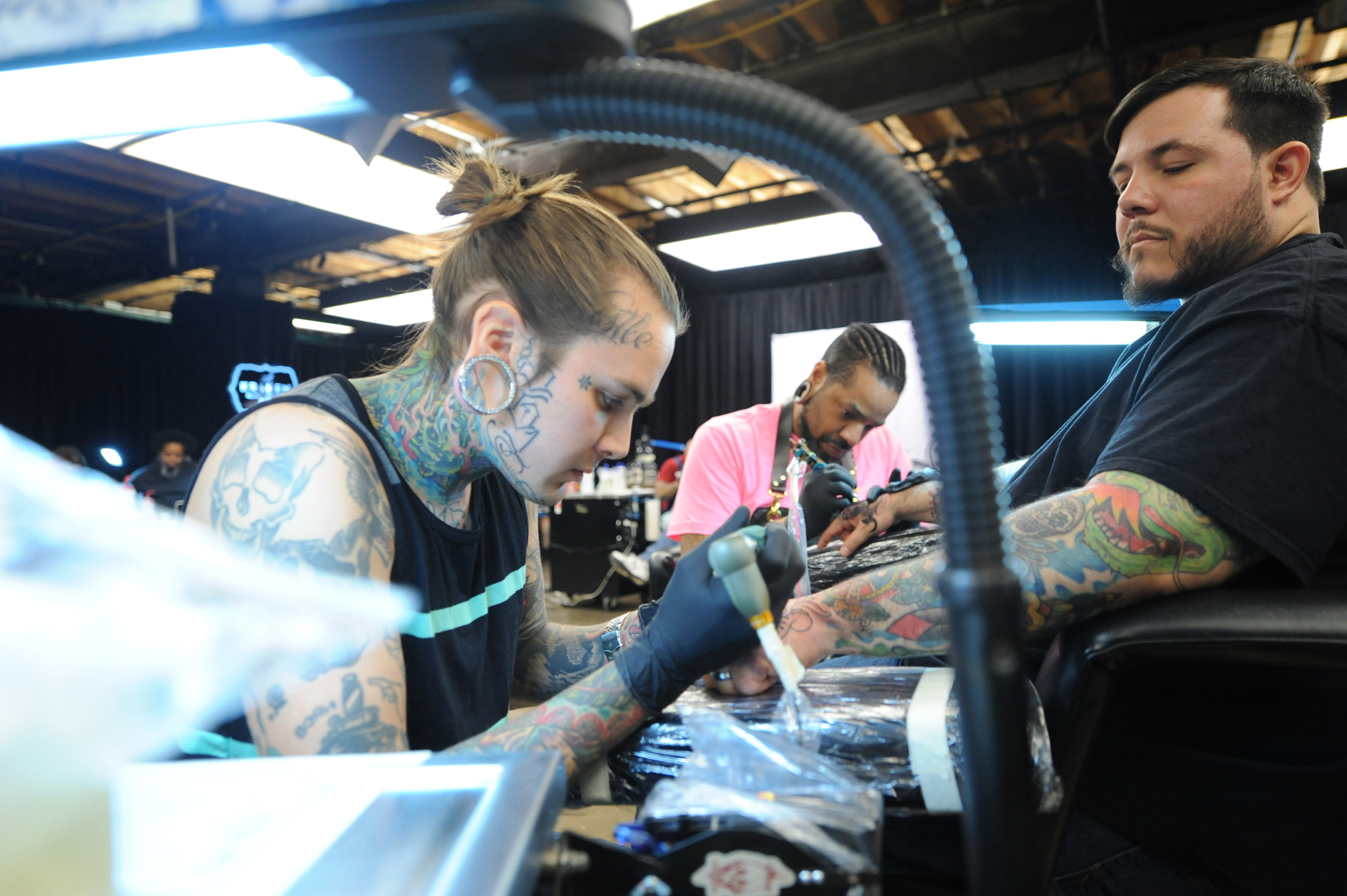 Three tattoo artists concentrating on inking clients at a tattoo convention