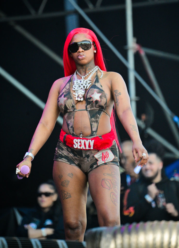 Sexyy Red performing in a star-patterned outfit with &quot;SEXY&quot; on shorts, accessorized with chain necklaces