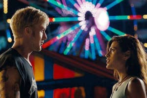 Ryan Gosling and Eva Mendes looking at each other in front of a lit up ferris wheel.