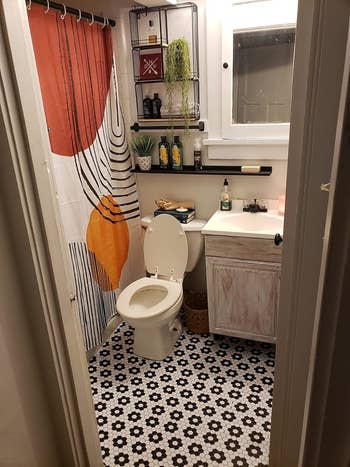 Bathroom with patterned shower curtain, tiled floor, and hanging plants; an idea for home decor shopping