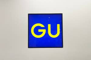 Framed artwork with bold "GU" text on blue background, displayed on a wall