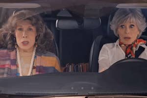 Two women expressing surprise while seated in a car, resembling characters from the television show "Grace and Frankie."