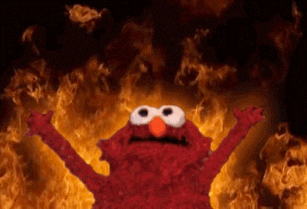 Elmo con las manos levantadas frente a llamas en el fondo