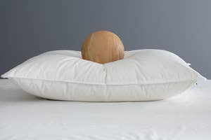 A round wooden object rests on a plush white pillow